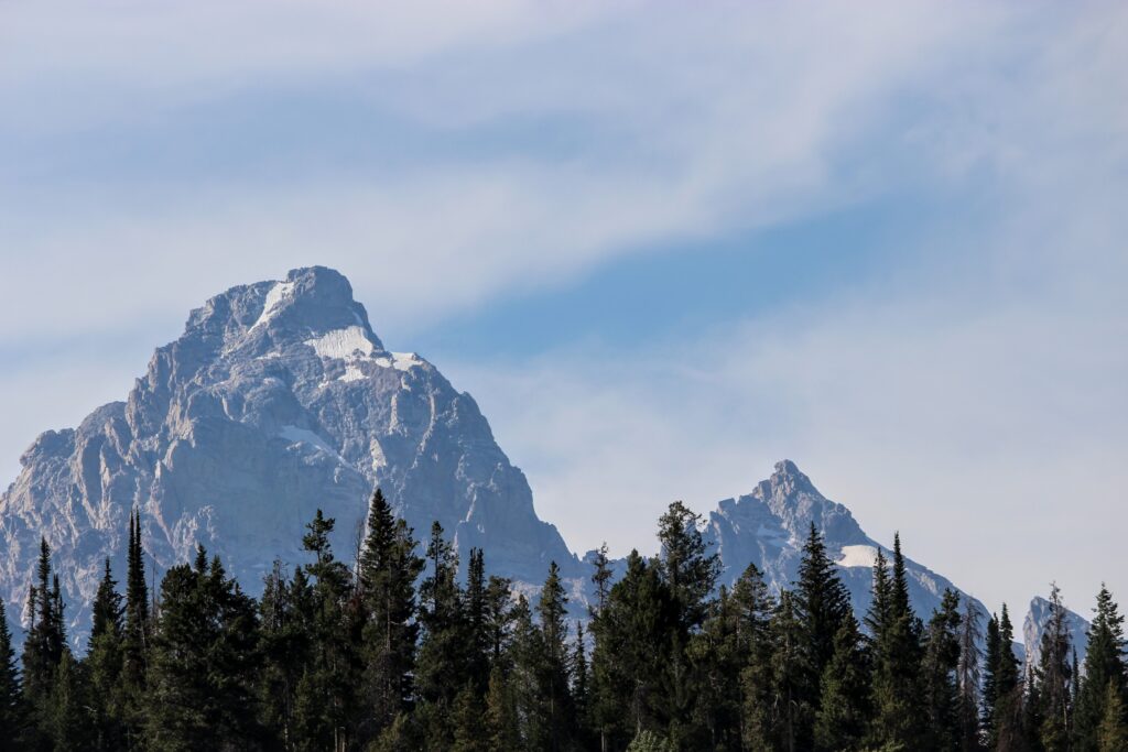 Scenic view of the Teton Mountain Range with snow caps and pine trees in Wyoming, USA.